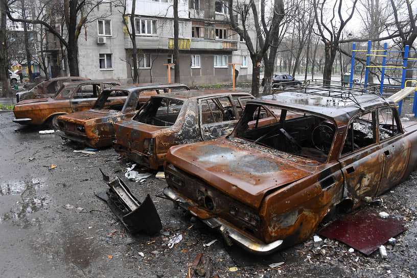 Разбитые и сожженные автомобили на парковке возле жилого дома в Левобережном районе Мариуполя