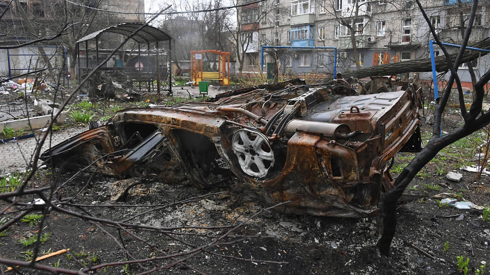 Искореженный после обстрела автомобиль во дворе жилого дома в Левобережном районе Мариуполя