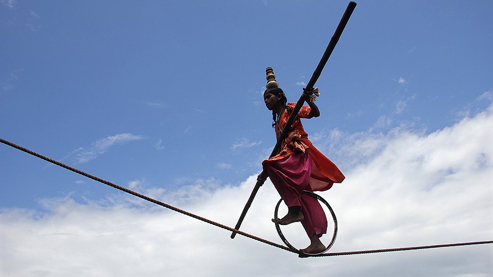 11 июля. Канатоходец балансирует на веревке во время представления в индийском Пури, расположенном в 65 км от города Бхубанешвар