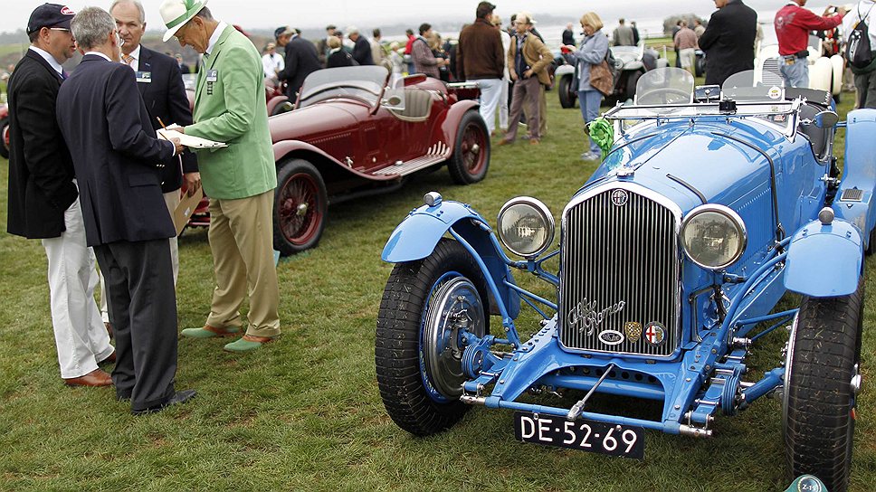 Судьи конкурса совещаются после осмотра автомобиля марки Alfa Romeo 8C Touring Le Mans 1933 года выпуска (справа)