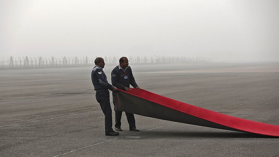 Сотрудники индийских ВВС разворачивают красную ковровую дорожку на аэродроме в Нью-Дели перед торжественной встречей президента Южной Кореи