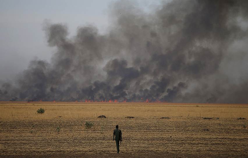 Южносуданский повстанец на фоне горящих полей в штате Верхний Нил