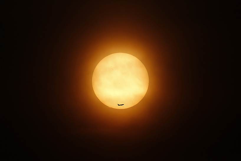 Пассажирский самолет на фоне заходящего солнца в Шанхае