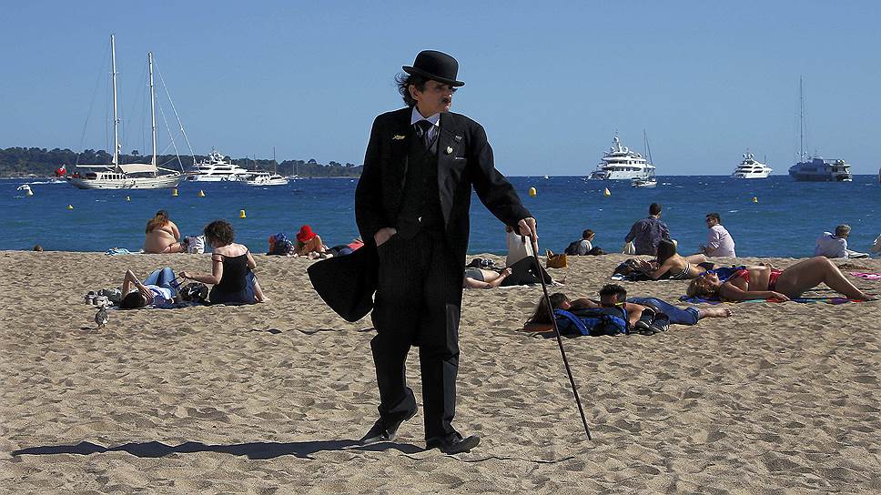 Мужчина в костюме Чарли Чаплина на пляже Канн