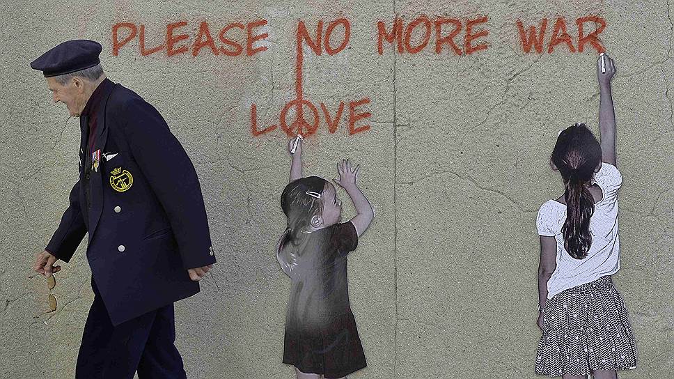 Британский ветеран нормандской кампании Пол Батлер идет мимо граффити с надписью «Пожалуйста, не надо больше войны. Любовь»