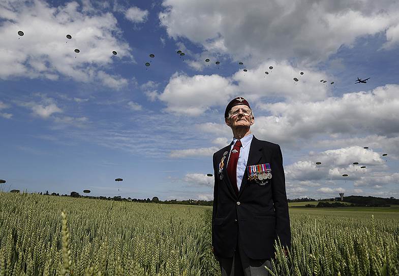 Ветеран Второй мировой войны Фред Гловер позирует на фоне парашютного десанта во французском Ранвиле во время празднования 70-й годовщины Нормандской операции