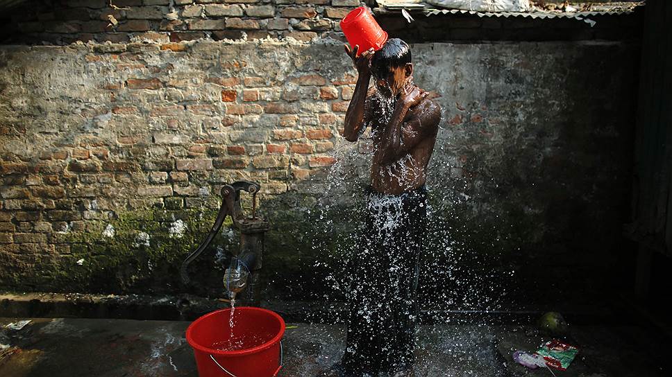 Молодой человек моется на улице Дакки, Бангладеш