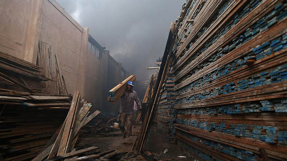 Ливийский рабочий уносит доски от очага пожара на складе леса в Бенгази
