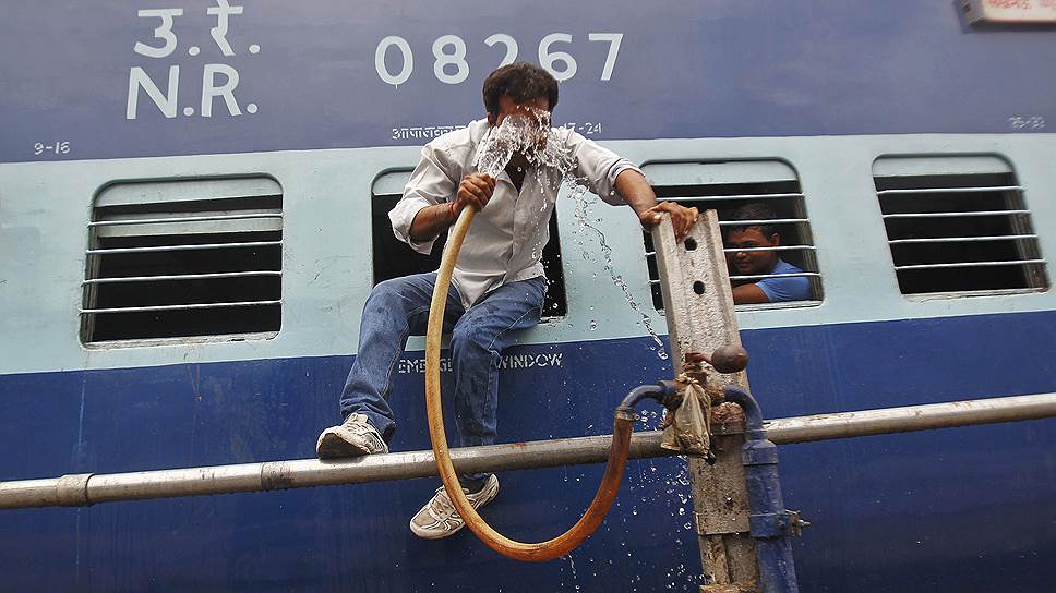 Пассажир индийского поезда умывается из шланга на станции в Аллахабаде