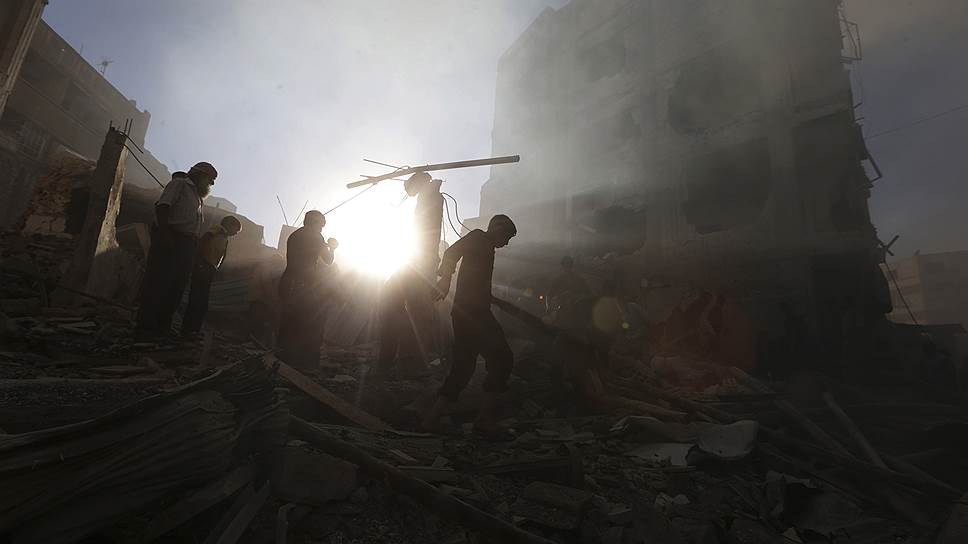 Местные жители осматривают дома, пострадавшие при авиаударе в Думе, Сирия