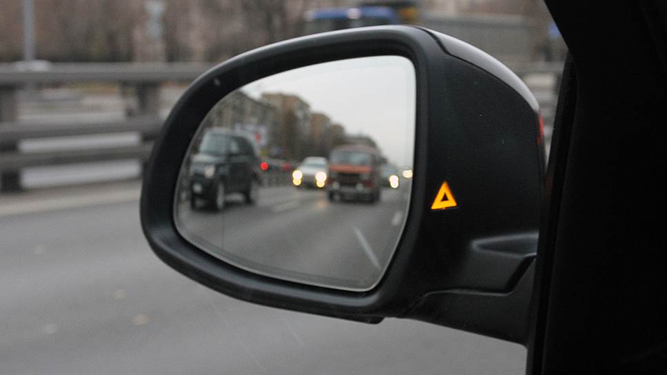 Желтый треугольник на боковом зеркале предупреждает о машинах в мертвой зоне