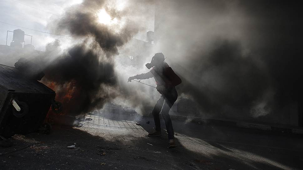 Рамалла, Палестина. Палестинский протестующий рядом с горящими шинами
