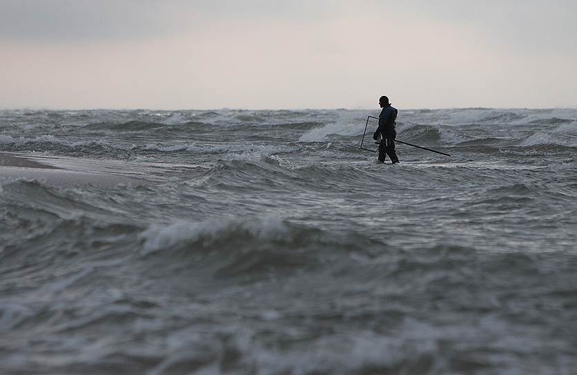 Калининградская область, Россия. Мужчина ловит янтарь в штормовом Балтийском море в поселке Янтарный