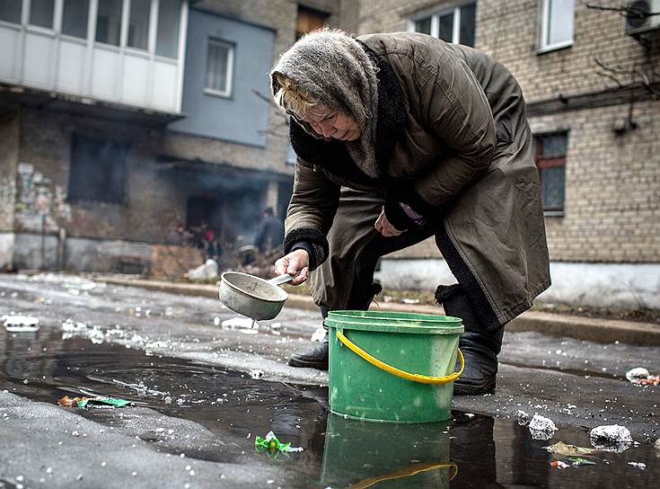 Дебальцево, Украина. Пожилая женщина набирает воду из лужи. Из-за ожесточенных боев в городе уже больше недели не работает водопровод, нет газа и электричества