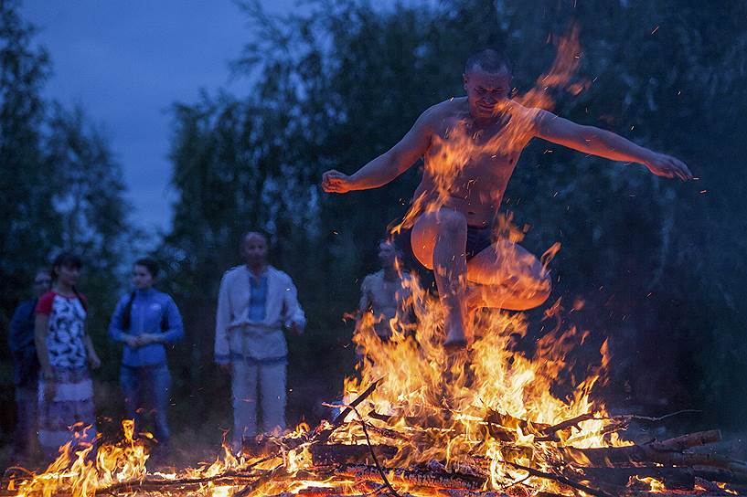 Омск, Россия. Мужчина прыгает через костер на праздновании дня Ивана Купалы