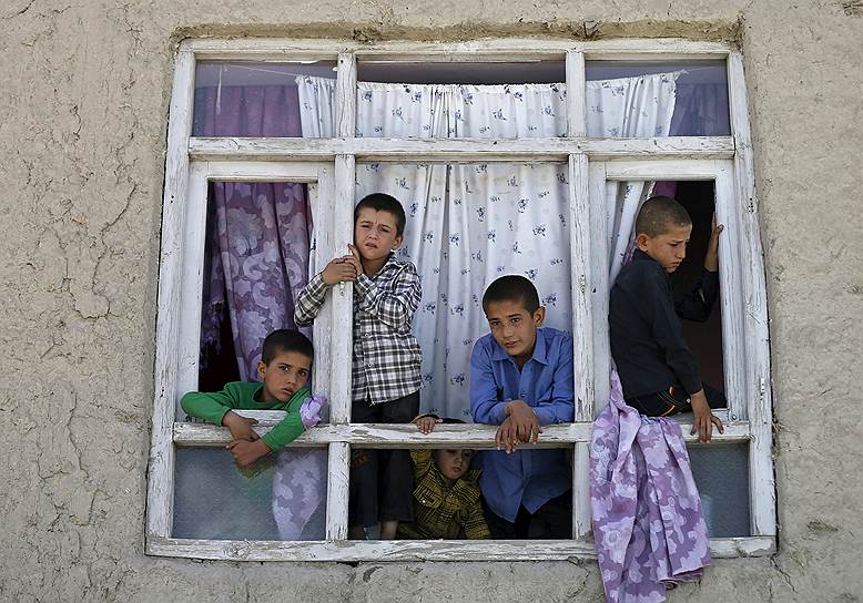 Кабул, Афганистан.  Дети смотрят из разбитого окна одного из домов неподалеку от места взрыва автомобиля на пропускном пункте в аэропорту Кабула