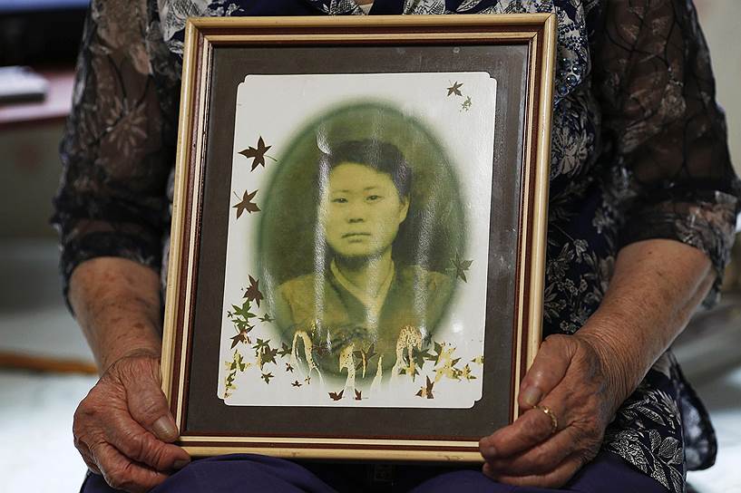 Ли Ок Сун показывает свою фотографию в одном из приютов для бывших секс-рабынь, который расположен в южнокорейском городе Кванджу. По словам женщины, она родилась в 1927 году в городе Пусан (Южная Корея) и в годы войны побывала во многих военных борделях. Снимок был сделан в 1947 году, через два года после капитуляции Японии, когда бывшая секс-рабыня пыталась получить гражданство в Китае. После окончания войны Ли не смогла вернуться в родной город, опасаясь слухов о своем прошлом. Она жила в Китае вплоть до 2001 года, после чего все-таки вернулась на родину