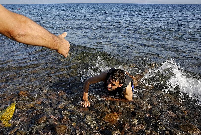 Лесбос, Греция. Местный житель помогает обессиленному мигранту, выпавшему из резиновой лодки, выбраться на берег