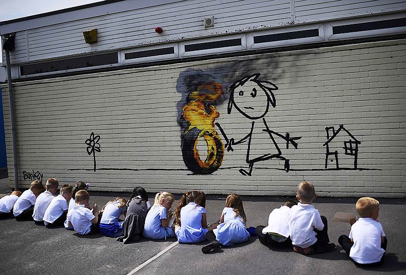 Граффити на стене школе в Бристоле, где учился Бэнкси. Так художник решил отблагодарить учебное заведение, назвавшее один из корпусов в его честь. Он подчеркнул, что дети, при желании, могут дополнить его рисунок, на котором изображена девочка, играющая с горящей шиной