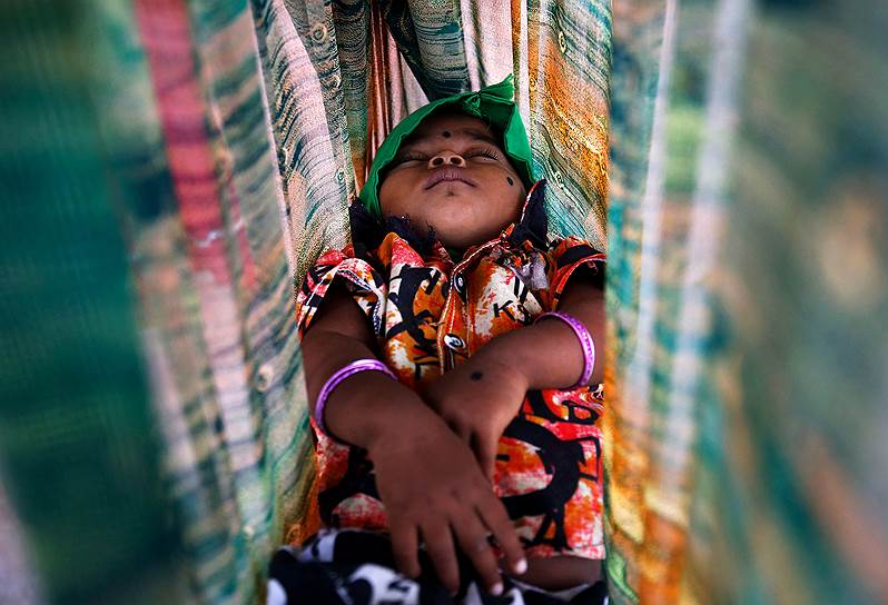 Бангалор, Индия. Ребенок спит в гамаке, пока его родители работают на стройке 