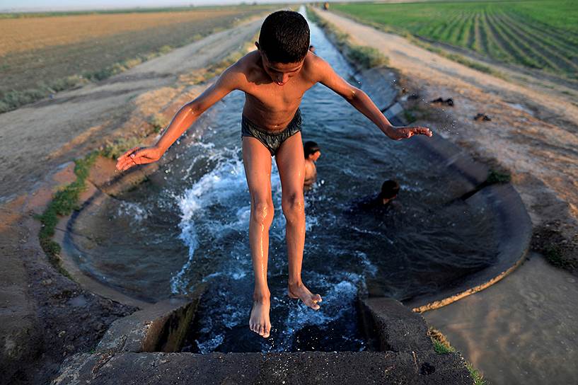 Ракка, Сирия. Мальчик купается в оросительном канале