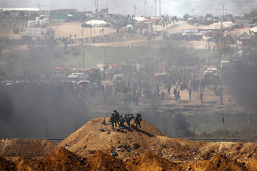 Сектор Газа. Группа израильских военных на фоне лагеря протестующих палестинцев