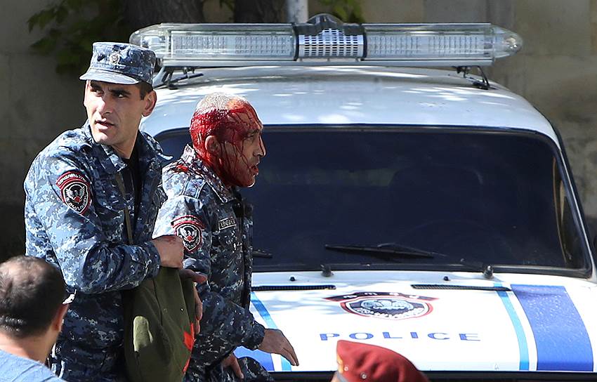 Армянский полицейский сопровождает коллегу, раненного в ходе беспорядков в Ереване