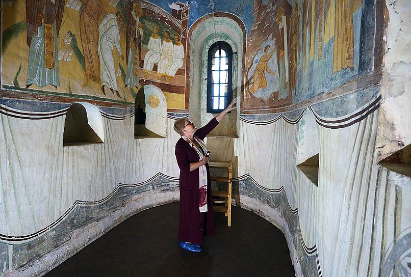 Хранитель собора Елена Шелкова показывает на фресках места, где таяние инея привело к подтекам.