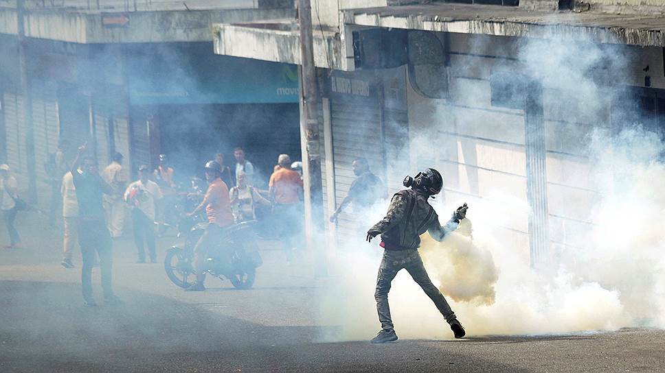 Демонстрант кидает обратно полиции шашку со слезоточивым газом в Тачире на западе Венесуэлы