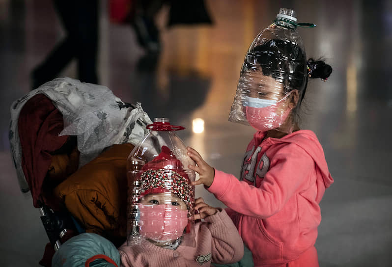 Пекин, Китай. Дети в защитных масках из пластиковых бутылок ждут вылета в аэропорту