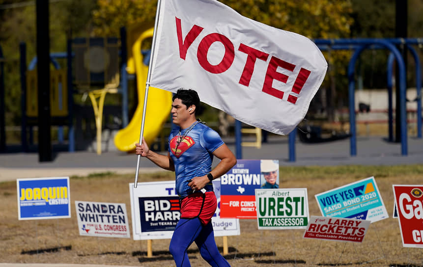 Сан-Антонио, Техас. Мужчина в костюме Супермена с флагом, призывающим проголосовать