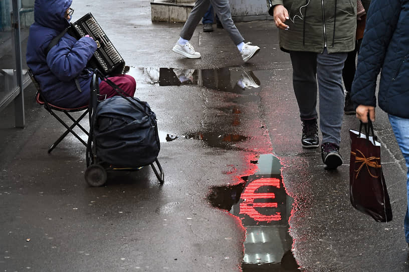 Отражение в луже знака евро на табло пункта обмена валют в Москве  