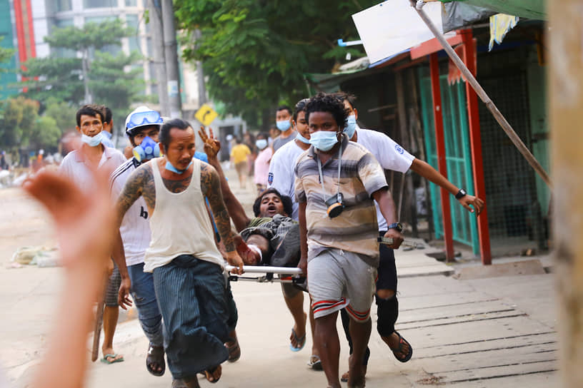 Протестующие переносят на носилках раненого во время демонстрации в Янгоне