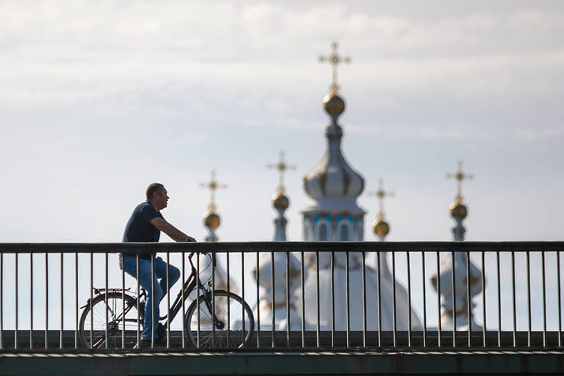 Санкт-Петербург. Мужчина на велосипеде на фоне куполов Смольного собора