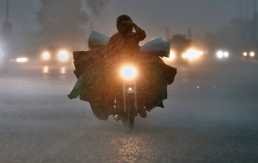 Исламабад, Пакистан. Мотоциклист едет во время ливня