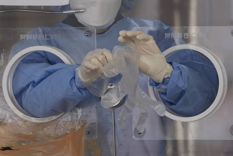 Сеул, Южная Корея. Медик надевает перчатки в клинике для больных коронавирусом