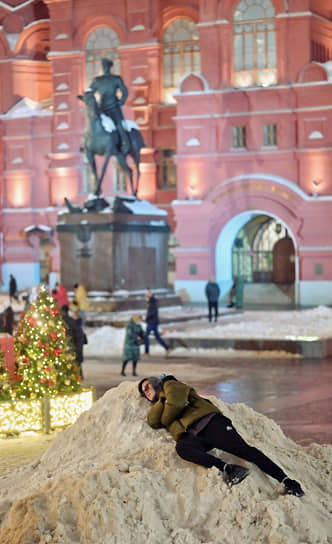 Москва, Россия. Молодой человек лежит на сугробе на Манежной площади