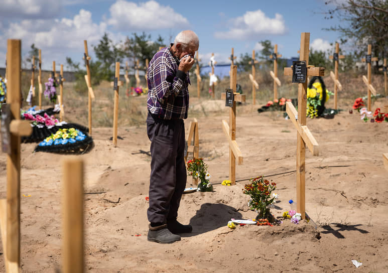 Мужчина плачет у могилы на новом кладбище в Северодонецке, где похоронены жертвы обстрелов