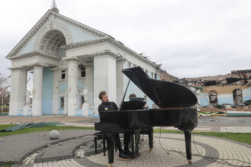 Литовский пианист Дариус Мажинтас играет перед пострадавшим от обстрелов домом культуры в Ирпене, пригороде Киева