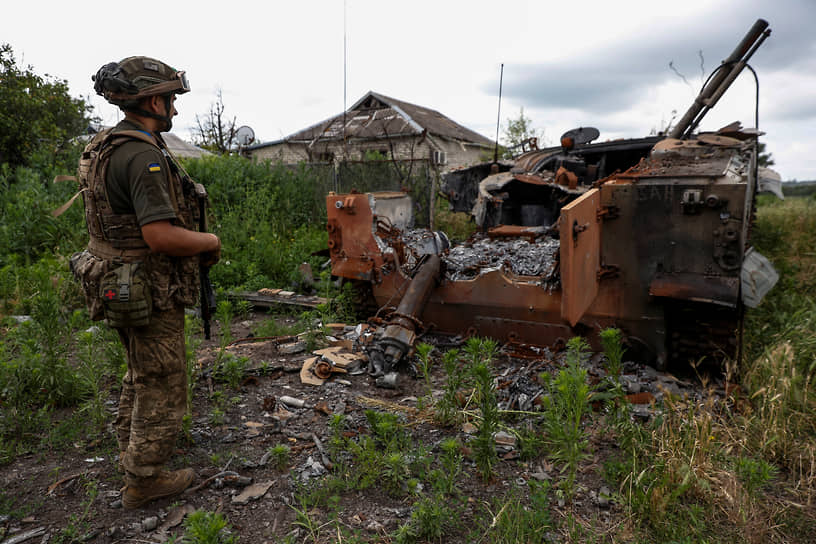 Украинский военнослужащий стоит около сгоревшей российской боевой машины в селе Благодатное