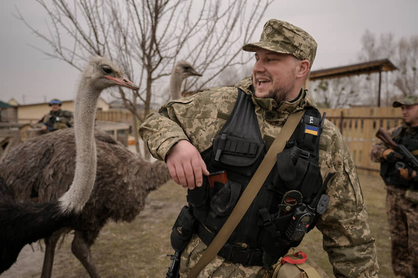 Киев, Украина. Военнослужащий отмахивается от страуса в частном зоопарке