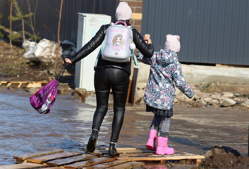 Деревня Куюки, Татарстан.  Женщина с ребенком переходят дорогу по деревянному помосту