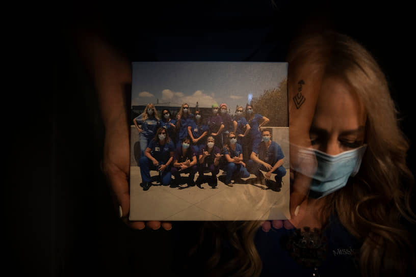 Медсестра Дебби Вутерс в Калифорнии, лечившая больных с коронавирусом в отделении интенсивной терапии,  держит групповой снимок со своими коллегами, 2021 год