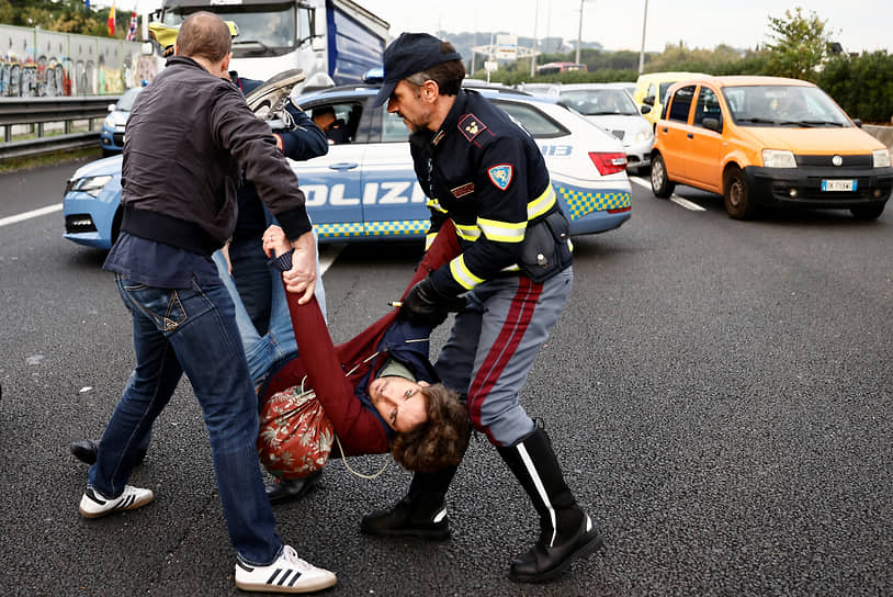 Рим, Италия. Полицейские уводят с дороги экоактивиста, заблокировавшего движение автомобилей