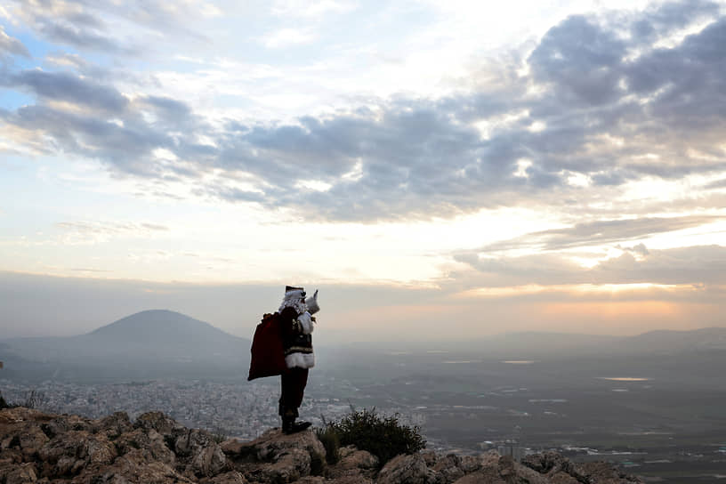 Израиль. Палестинец в костюме Санта-Клауса позирует на фоне горы Фавор