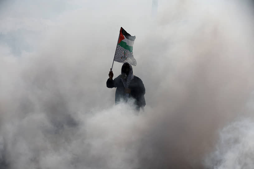 Каландия, западный берег реки Иордан. Палестинский протестующий в облаке слезоточивого газа