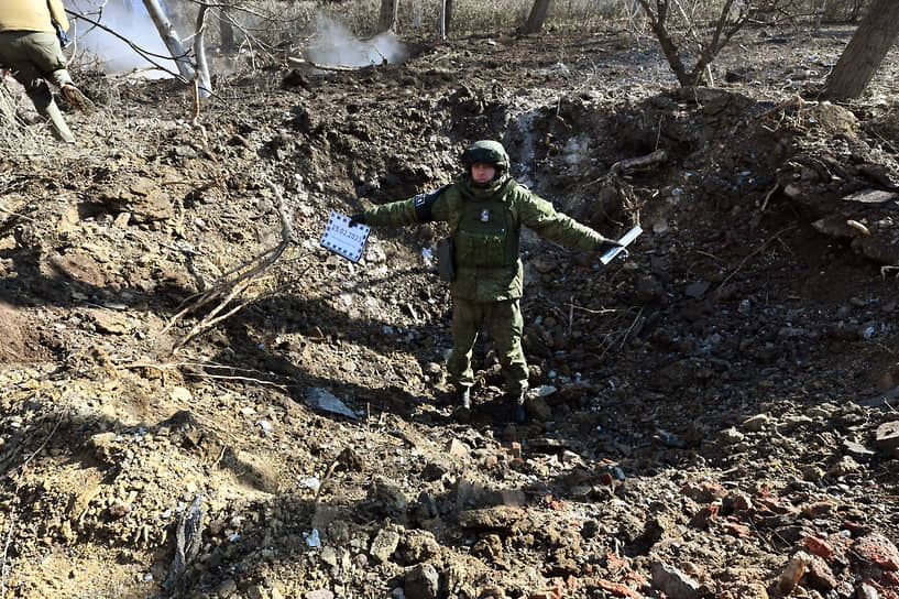 Сотрудник Совместного центра контроля и координации ДНР стоит в воронке, образованной после падения снаряда