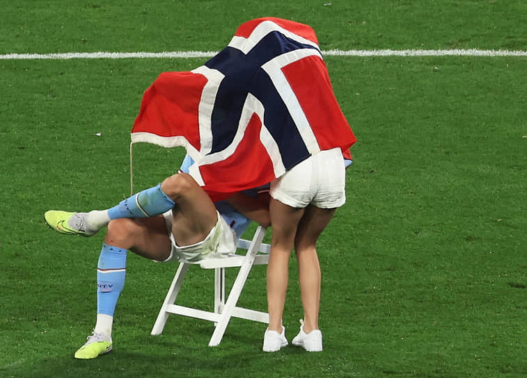 Эрлинг Браут Хааланд из «Манчестер Сити» и его девушка Изабель Йохансен с флагом Норвегии на поле после победы команды в Лиге чемпионов