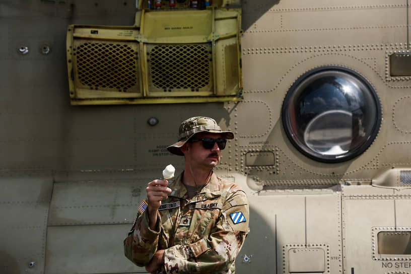 Американский военнослужащий стоит рядом с тяжелым транспортным вертолетом CH-47F Chinook производства концерна Boeing