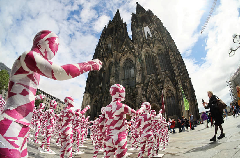 Кельн, Германия. Детские манекены, обмотанные лентой и установленные перед Кельнским собором немецким художником Деннисом Йозефом Мезегом в знак протеста против насилия над детьми